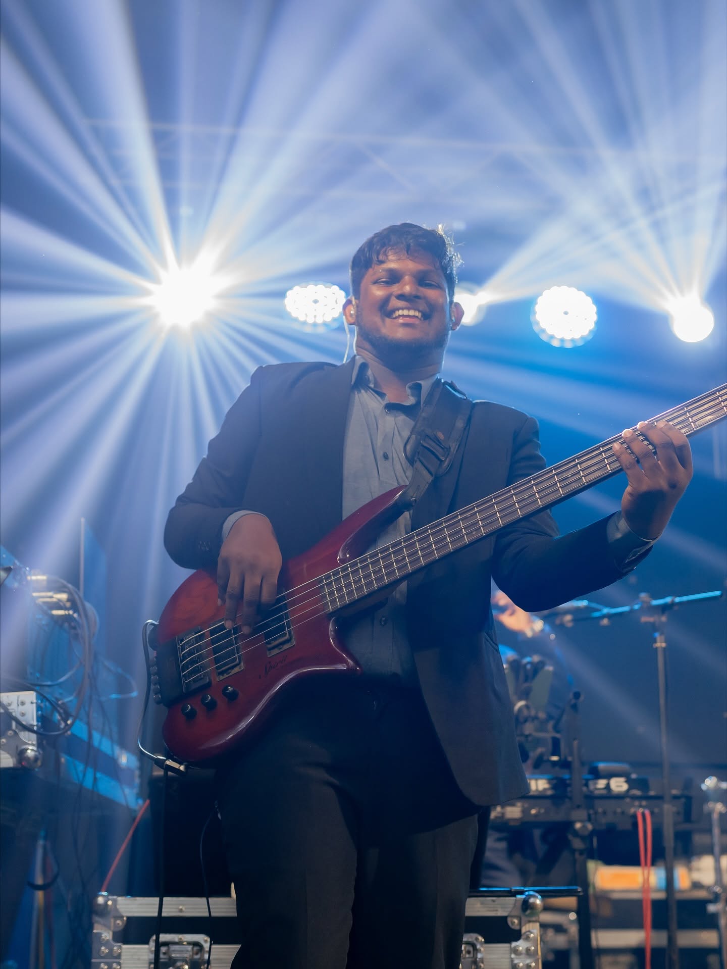 The bassist smiling under blue stage beams