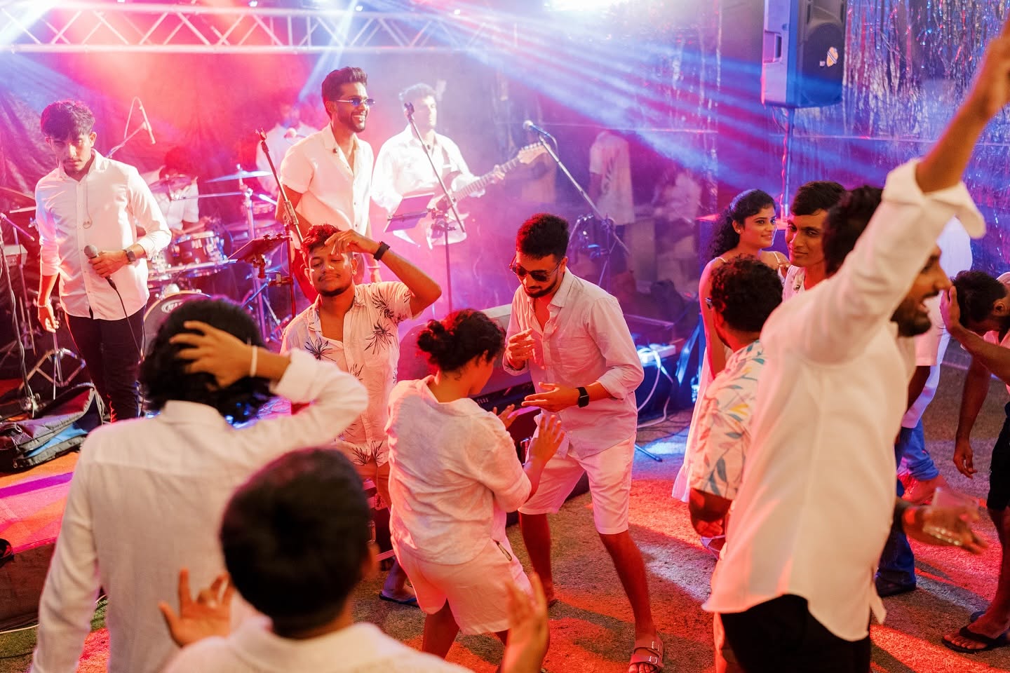 Wedding guests in white dancing in front of the band