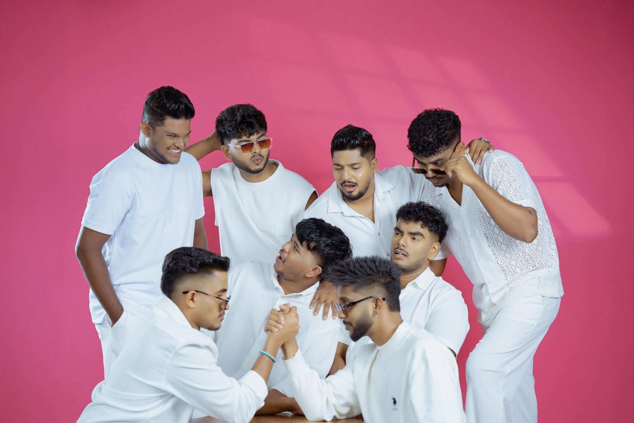 The band in matching all-white outfits on a pink backdrop